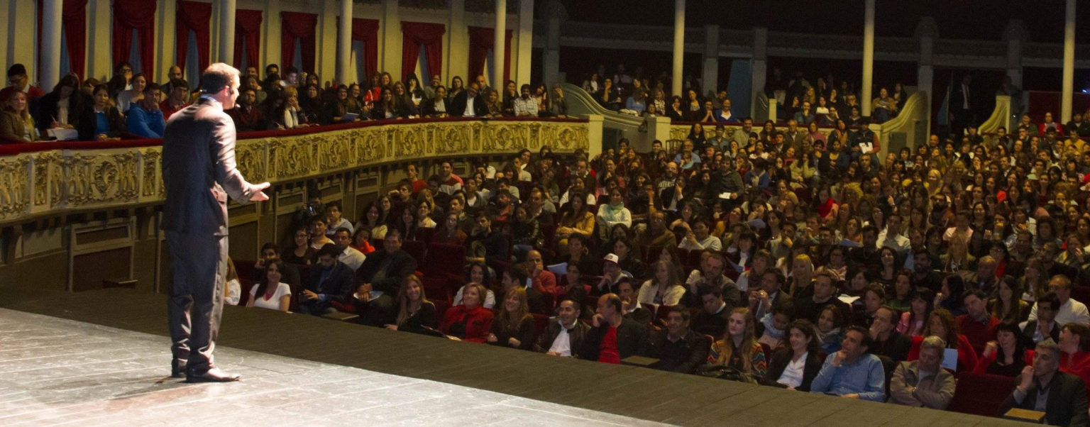 Pablo Cúnsolo hablando frente a un teatro colmado de público